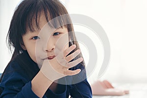 Asian kid cute girl sucking the finger her thumb