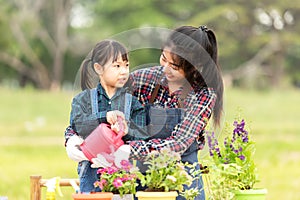 Asian kid daughter helping mother water and sapling the plant tree outdoors in nature spring