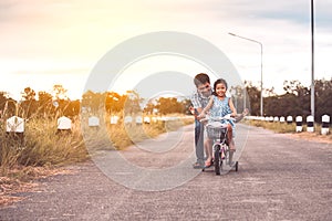 Asian kid girl having fun to ride bicycle with father