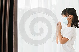 Asian kid girl praying wearing mask for protect pm2.5 and Covid-19 Little girl hand praying for thank god