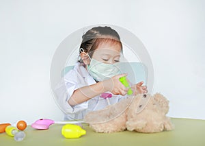 Asian Kid girl with protect mask plays doctor with her bear doll