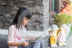 Asian kid girl using tablet for online learning.