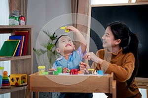 Asian kid and his teacher play doh togather in class room in preschool photo