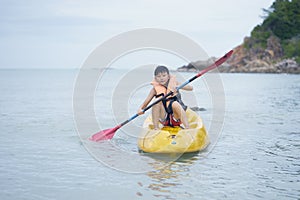 Asian kid kayaking alone on the sea wearing life vest