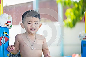 Asian kid playing in inflatable baby swimming pool on hot summer