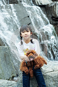 Asian kid playing with poodle dog