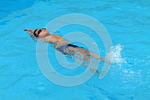 Asian kid swims in swimming pool - back stroke kick style