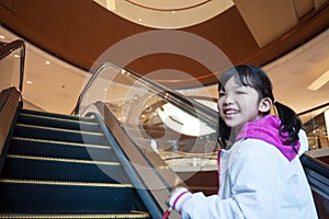 Asian kid taking escalator