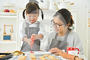 Asian Kid and young mother decorating cookies.