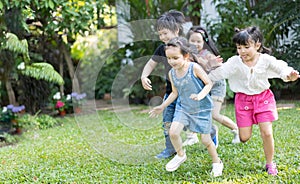 Asian kids playing outdoors with friends. little children play football soccer at nature park.