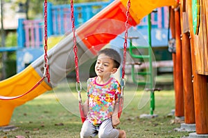 Asian Kids playing swing at playground outdoor with happy smile