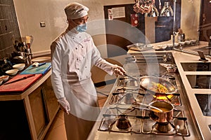 Asian kitchen worker frying vegetables on big flame