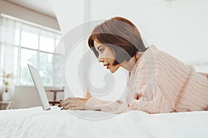 Asian Korean woman lying on the bed using laptop