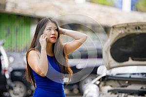 Asian Korean woman in stress stranded on street suffering car engine failure having mechanic problem calling on mobile phone for
