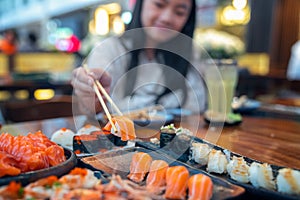 Asian lady eat a Salmon fish sashimi and Sushi in Japanese restaurant