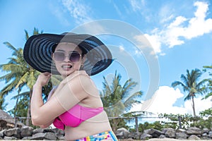 An asian lady feels an uncomfortable sunburn while at a tropical beach. Concept of UV protection