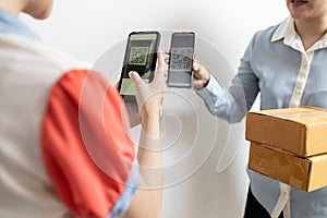 Asian lady girl receiving parcel post box from delivery service,pay deliver with smartphone to scan QR code payment purchase,pay