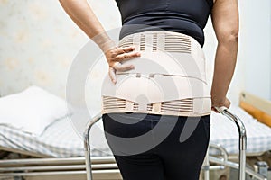 Asian lady patient wearing back pain support belt for orthopedic lumbar.