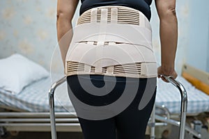 Asian lady patient wearing back pain support belt for orthopedic lumbar with walker