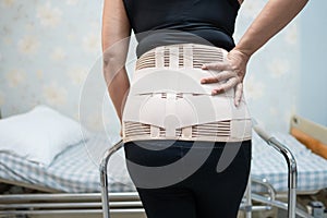 Asian lady patient wearing back pain support belt orthopedic lumbar with walker