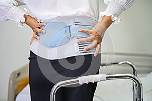 Asian lady patient wearing back pain support belt for orthopedic lumbar with walker