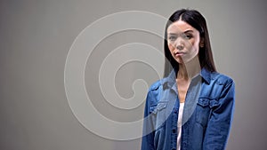 Asian lady suspiciously looking at camera, isolated on grey background, mistrust