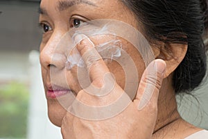 Asian lady woman applying cream skincare treatment to solve blemishes or melasma and dark spots in her face photo