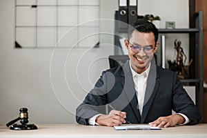 Asian lawyer man working on table office Writing a document, law and justice concept.
