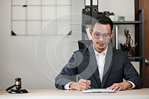 Asian lawyer man working on table office Writing a document, law and justice concept.