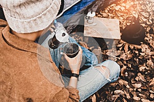 Asian lesbian sitting pouring hot water of espresso with Italian Moka coffee pot drinking in a forest on vacation, traveler