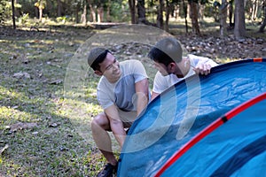 Asian LGBTQ couple camping together Set up a tent on the grass During the weekend vacation