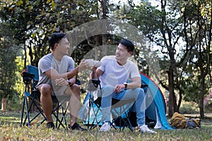 Asian LGBTQ couple drinking coffee in a romantic camping tent. LGBTQ couple drinking coffee in a camping tent, enjoying