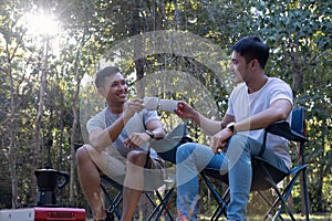 Asian LGBTQ couple drinking coffee in a romantic camping tent. LGBTQ couple drinking coffee in a camping tent, enjoying