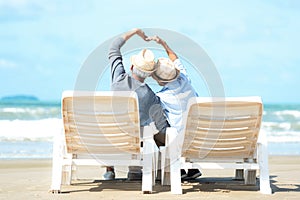 Asian Lifestyle senior couple raise hands and sitting on the beach happy in love romantic and relax time.