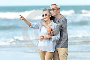 Asian Lifestyle senior couple walking chill and pointing on the beach happy in love romantic and relax time after retirement.