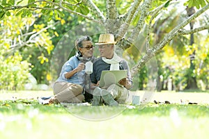 Asian Lifestyle senior elderly retire couple drinking coffee and working online  in the nature park happy and relax time.