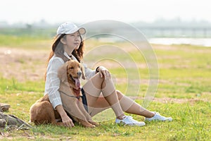 Asian lifestyle woman playing  with golden retriever friendship dog so happy and relax near the road