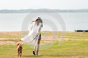 Asian lifestyle woman playing and running  with golden retriever friendship dog in sunrise outdoor