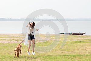 Asian lifestyle woman playing and running  with golden retriever friendship dog in sunrise outdoor the summer river park.