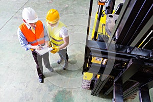 Asian lift truck driver and foreman in storage