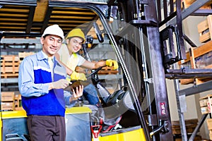 Asian lift truck driver and foreman in storage