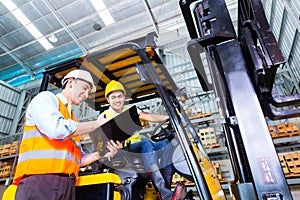 Asian lift truck driver and foreman in storage