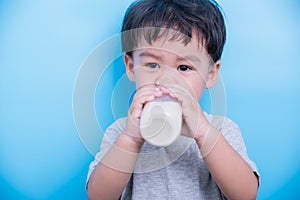 Asian little baby child boy about 2 year drinking milk from bottle glass