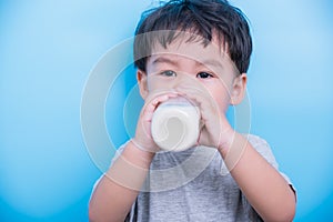 Asian little baby child boy about 2 year drinking milk from bottle glass