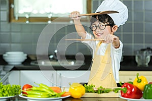 Asian little boy cooking and cutting vegetables for mixed healthy salad in the  kitchen, so happy and relax for leaning and educat