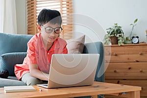 Asian little boy doing homework, typing, Asia male student happy smile using laptop computer. Homeschooling, Concept online