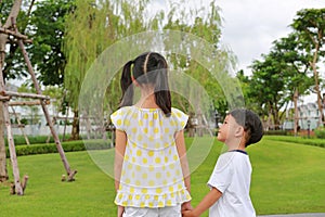 Asian little boy and girl child with hand in hand while together in the garden. Asian Children in green park