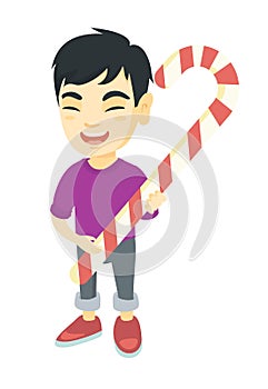 Asian little boy holding christmas candy cane.