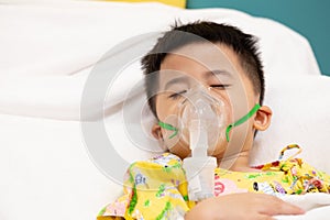 Asian little boy making inhalation with nebulizer at hospital.