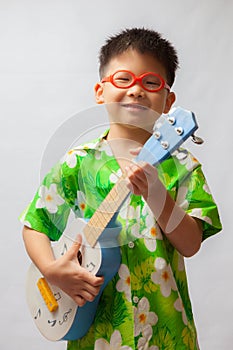 Asian little boy playing ukulele